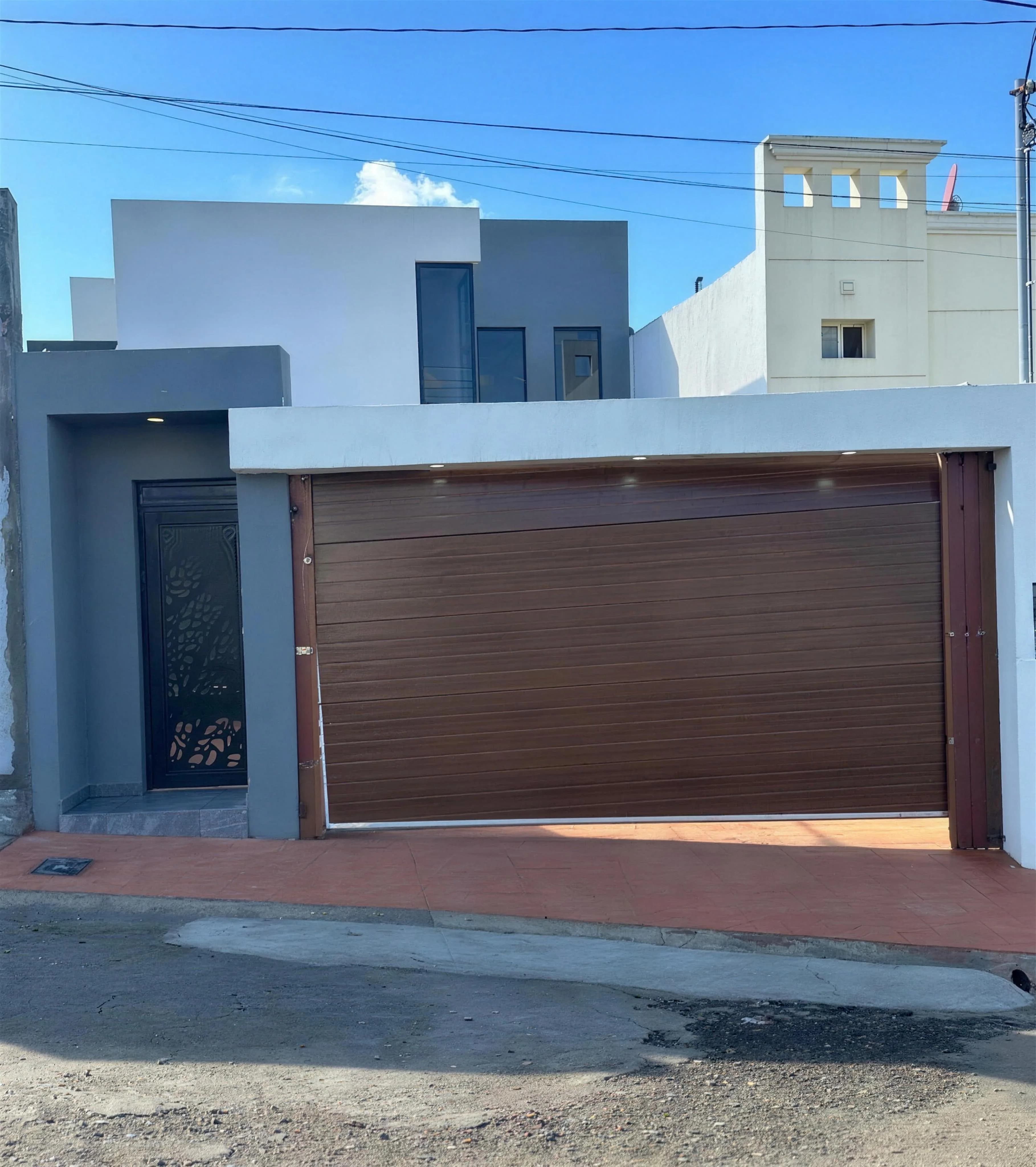 Casa El Lago terminada: fachada contemporánea en gris y blanco con portón de madera